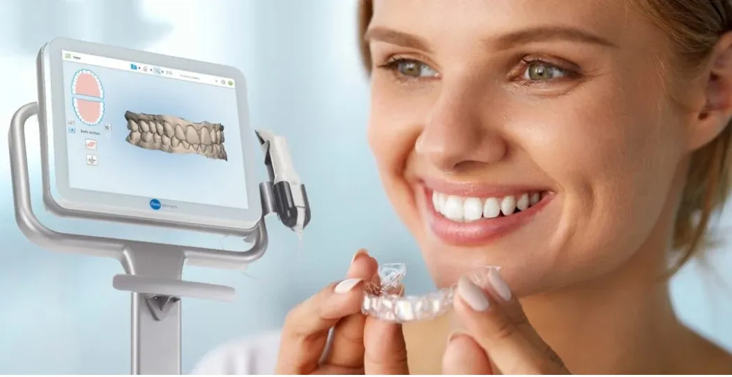 Woman smiling while holding a clear Invisalign aligner