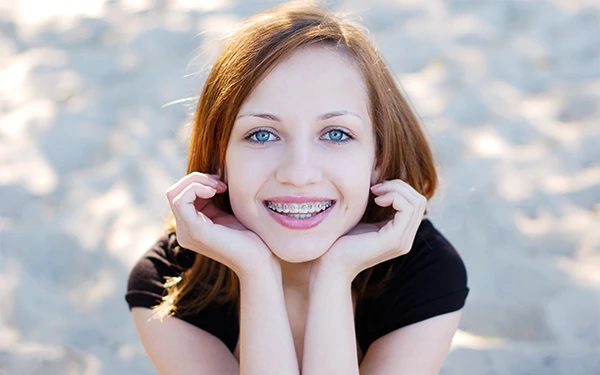 Girl with braces resting her chin on her hands and smiling