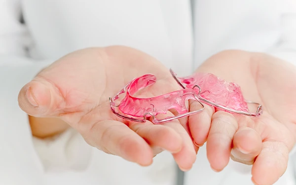 Clinician holding a pink removable retainer